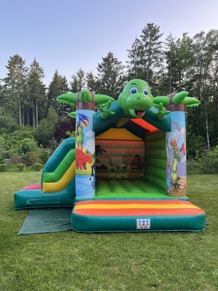 Hüpfburg „Lustiger Dino“ mit Rutsche auf einer Wiese